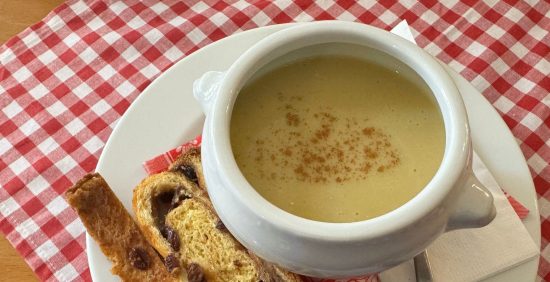 Creamy potato soup with cinnamon and raisin bread on checkered tablecloth, kirchtagsuppe