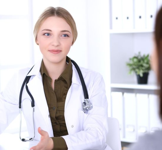 Young woman doctor and patient at medical examination in hospital office. Khaki colored blouse of therapist looks good. Medicine,  healthcare and doctor's appointment concept.